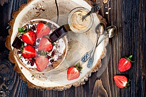 Chocolate almond butter maca smoothie bowl topped with sliced strawberries, chopped chocolate and pomegranate seeds