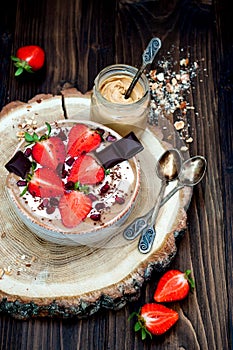 Chocolate almond butter maca smoothie bowl topped with sliced strawberries, chopped chocolate and pomegranate seeds