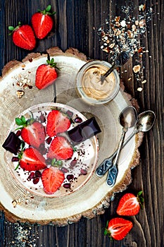 Chocolate almond butter maca smoothie bowl topped with sliced strawberries, chopped chocolate and pomegranate seeds