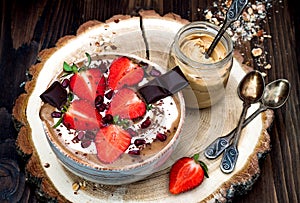 Chocolate almond butter maca smoothie bowl topped with sliced strawberries, chopped chocolate and pomegranate seeds