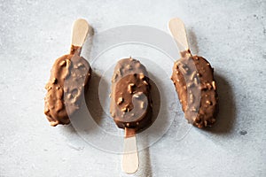 Chocolate almond ice-cream on a wooden stick on a gray background. Top view