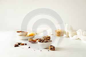 Chocolate, almonds, orange and oatmeal energy balls in white bowl on white background