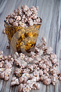 Chocolate aroma popcorn in the yellow glass and on the brown wood table