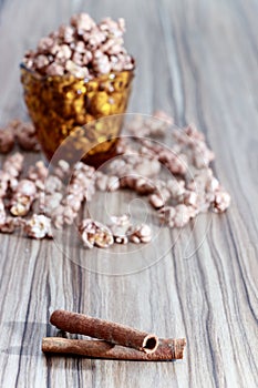 Chocolate aroma popcorn in the yellow glass and on the brown wood table with cinnamon and white flower background