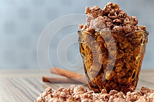 Chocolate aroma popcorn in the yellow glass and on the brown wood table with cinnamon and white flower background