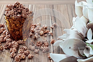 Chocolate aroma popcorn in the yellow glass and on the brown wood table with white flower background