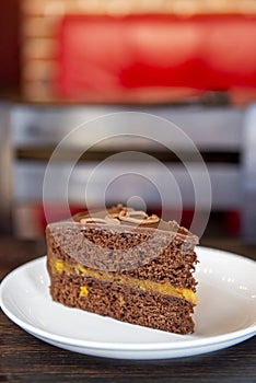 Chocolate Austrian dessert Sacher with apricot jam. One slice of traditional Sacher cake served on a white plate