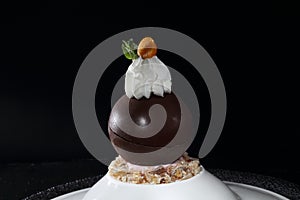 Chocolate ball with whipped cream on a black background. Dessert