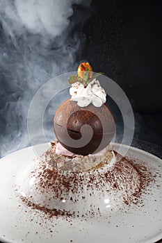 Chocolate ball with whipped cream on a black background. Dessert
