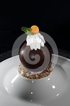 Chocolate ball with whipped cream on a black background. Dessert