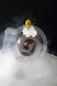 Chocolate ball with whipped cream on a black background. Dessert