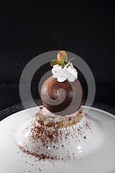 Chocolate ball with whipped cream on a black background. Dessert