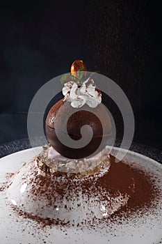 Chocolate ball with whipped cream on a black background. Dessert