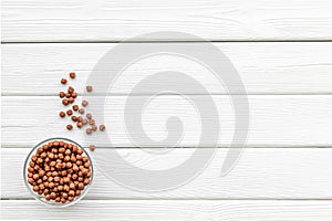 Chocolate balls, corn cereals in bowls on white wooden background top view space for text