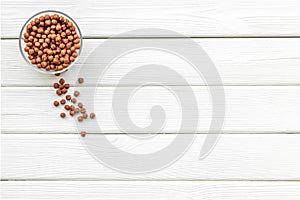 Chocolate balls, corn cereals in bowls on white wooden background top view space for text