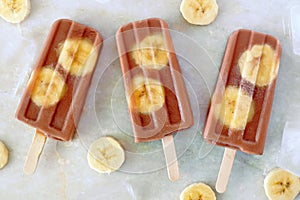 Chocolate banana popsicles on white marble