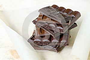 Chocolate bar black, milky, porous chocolate stacked on a parchment paper and a wooden board. Chocolate Day