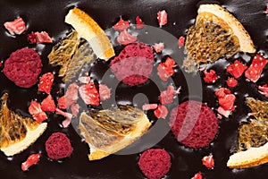 Chocolate bar with freeze dried oranges and berries as background, closeup