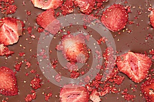 Chocolate bar with freeze dried strawberries as background, closeup