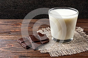 Chocolate bar and glass of milk on wooden.