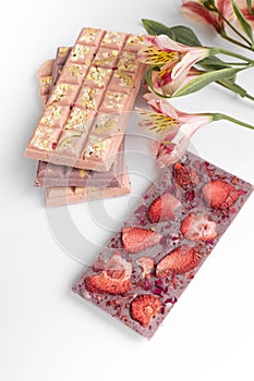 chocolate  bar of handmade glutenfree chocolate  with nuts and dry strawberry on white background with flowers