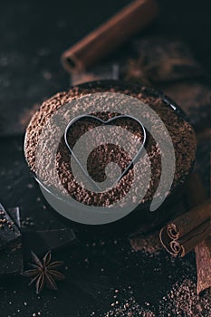 Chocolate bar pieces with cocoa powder and heart shape on dark background, cope space