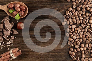 Chocolate bar, shelled hazelnuts, roasted coffee beans, cinnamon on wooden background