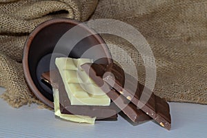 Chocolate bars in a clay bowl on a wooden table with burlap photo