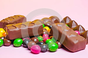 Chocolate bars, colorful candy, sweets on a pink background