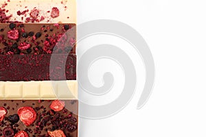 Chocolate bars with freeze dried berries on white background, flat lay. Space for text