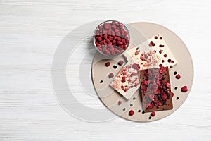 Chocolate bars with freeze dried fruits on white wooden table, top view. Space for text