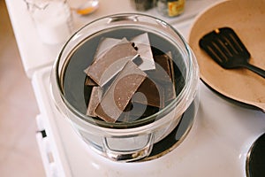 Chocolate bars are melted in a glass bowl on a steam bath.