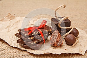 Chocolate bars with nuts and chocolate candies on pack paper