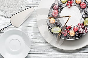 chocolate berry cake on plate over white wooden background