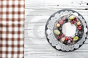 Chocolate berry cake on plate over white wooden background