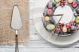 Chocolate berry cake on plate over white wooden background
