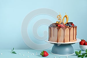 Chocolate birthday cake with berries, cookies and number 30 golden candles on blue wall background, copy space