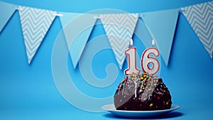 chocolate birthday cake with a burning candle number sixteen, 16 on a blue background. Copy space. place for text