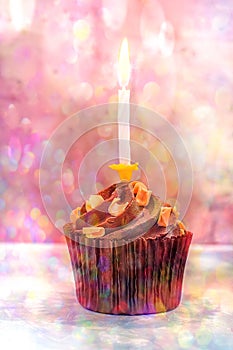 Chocolate Birthday Cupcake with Buttercream Caramel Swirl Sprinkles. Single Lit Burning Candle. Colorful Confetti Lights Flare
