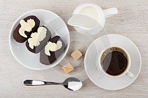 Chocolate biscuit cakes with buttercream in saucer, jug milk, co