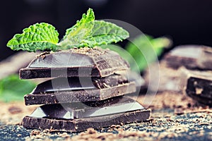 Chocolate. Black chocolate. A few cubes of black chocolate with mint leaves. photo