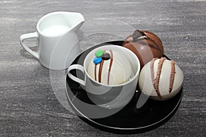 chocolate bombs in mug with hot milk, filled with marshmallows and white chocolate on vintage gray background