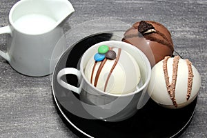 Chocolate bombs in mug with hot milk, filled with marshmallows and white chocolate on vintage gray background