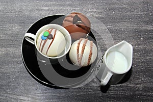 Chocolate bombs in mug with hot milk, filled with marshmallows and white chocolate on vintage gray background