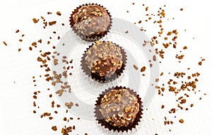 Chocolate bonbons with peanut pieces on white background