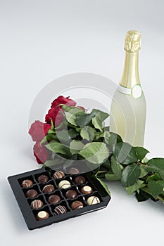 Chocolate box, roses and champagne bottle on white background