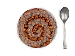 Chocolate breakfast cereal with spoon, top down view isolated on white