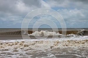 Chocolate brown waves roll toward the shore under a stormy sky after a hurricane photo
