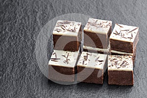 Chocolate brownie bites with sparklng chocolate topping on black stone background