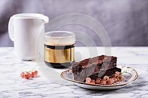 Chocolate brownie cake with berries red currant and cup of coffee